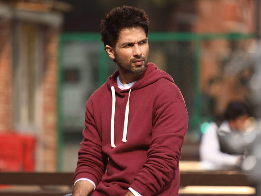 Shahid Kapoor in a maroon hoodie with a serious expression against a blurred urban background HD wallpaper