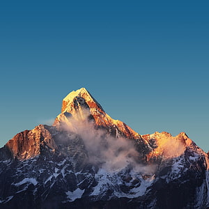 Majestic Snow-Capped Mountain Peak Bathed in Golden Sunrise Light Against a Clear Blue Sky HD phone wallpaper