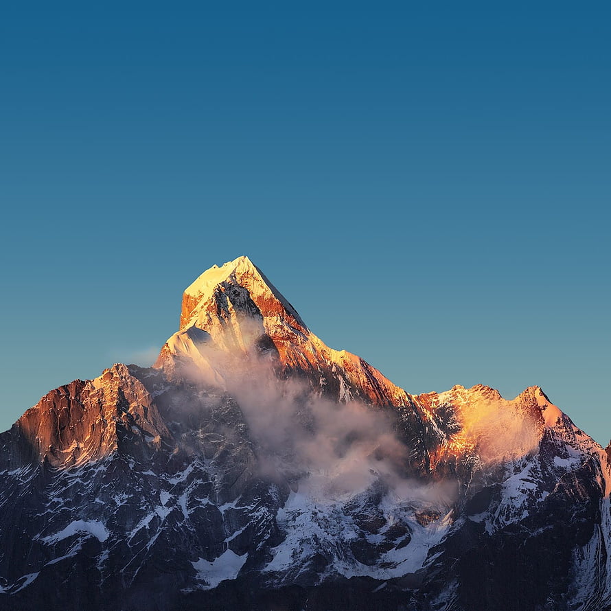 Majestic Snow-Capped Mountain Peak Bathed in Golden Sunrise Light Against a Clear Blue Sky HD phone wallpaper