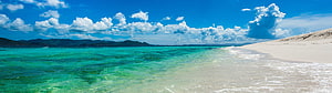 Stunning Panoramic View of Turquoise Ocean Waves Lapping Against White Sandy Beach Under Blue Sky HD wallpaper