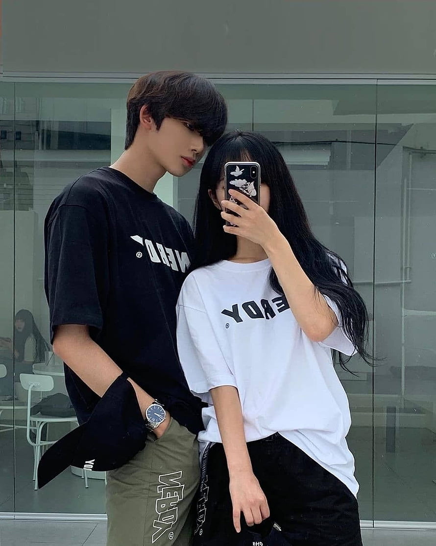Young couple taking a mirror selfie wearing matching black and white oversized graphic t-shirts and casual streetwear HD phone wallpaper