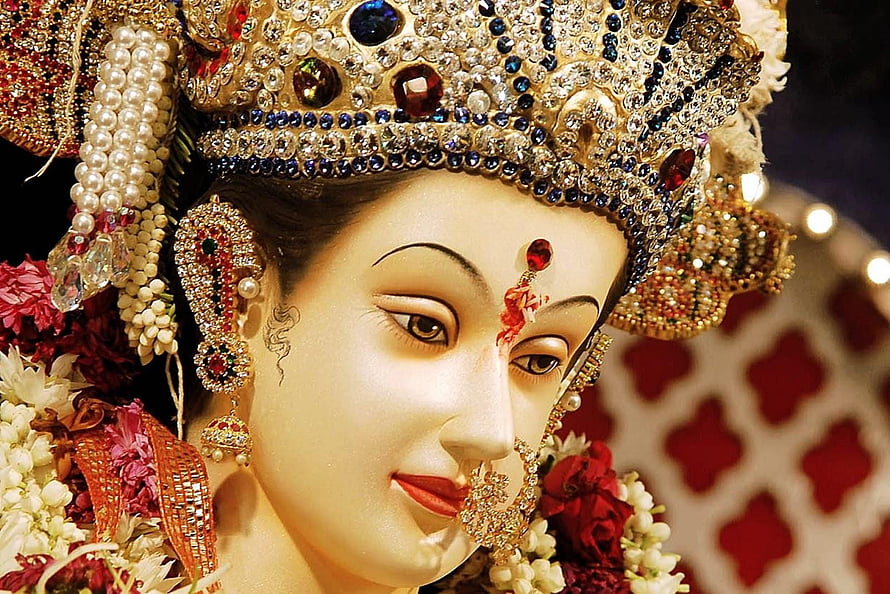 Close-up of a beautifully adorned Hindu deity statue with intricate jewelry and floral garlands HD wallpaper