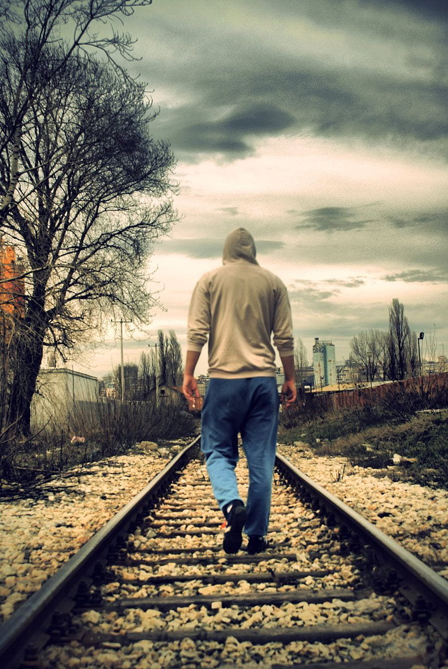 Man in Hoodie Walking Alone on Abandoned Railway Tracks Under Overcast Sky, Lonely Man on Dog, sad boy full screen HD phone wallpaper