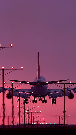 Airplane Landing on Runway at Sunset with Purple Sky and Red Lights HD phone wallpaper