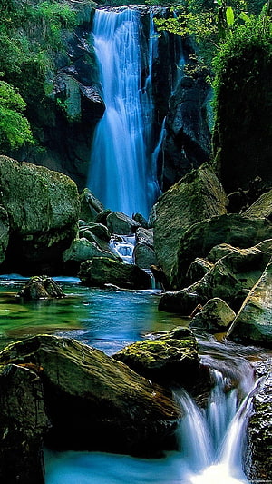 Serene Blue Waterfall Cascading Over Mossy Rocks in Lush Forest HD phone wallpaper