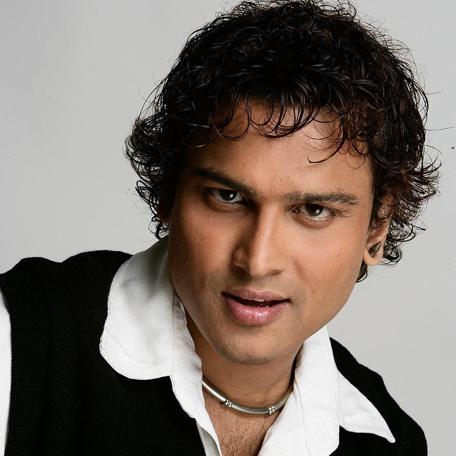 Portrait of a man with curly dark hair wearing a black vest over a white shirt and a silver necklace, Zubeen Garg HD phone wallpaper