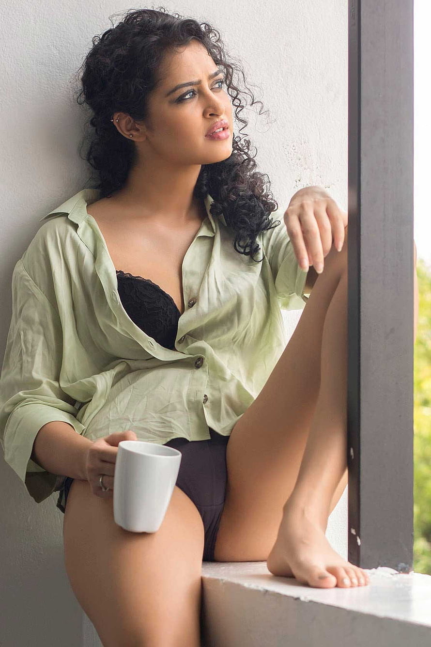 Apsara Rani in a light green shirt and black lace bra, seated on a windowsill holding a white mug HD phone wallpaper