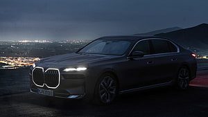 BMW i7 Electric Luxury Sedan Parked on Hilltop at Night with City Lights HD wallpaper