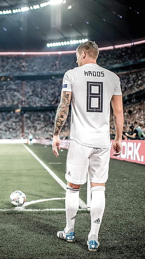 Toni Kroos in white Real Madrid kit standing on the pitch with a soccer ball at his feet HD phone wallpaper