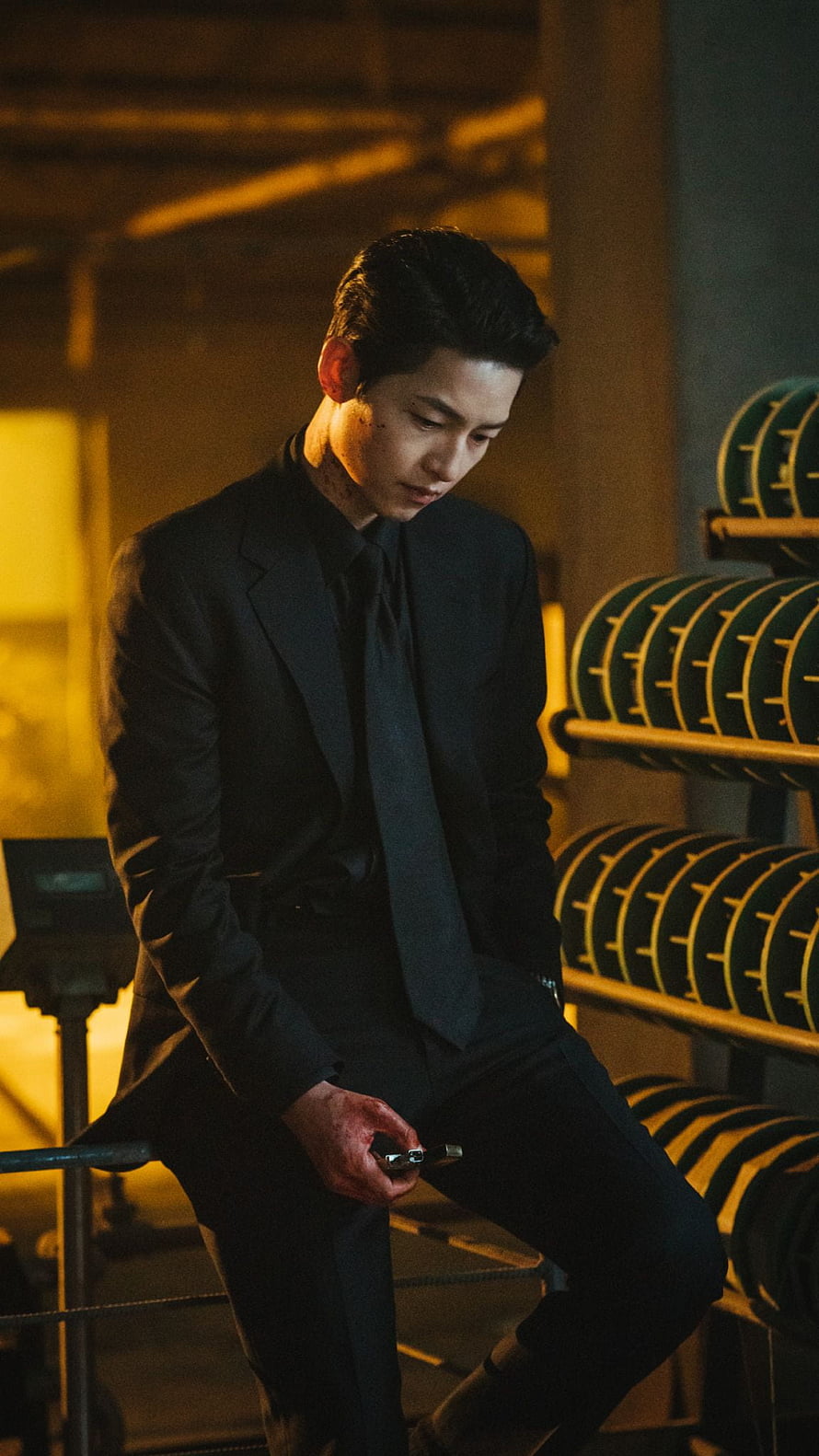 Song Joong Ki as Vincenzo Cassano in a dark suit holding a gun in a moody gym setting HD phone wallpaper