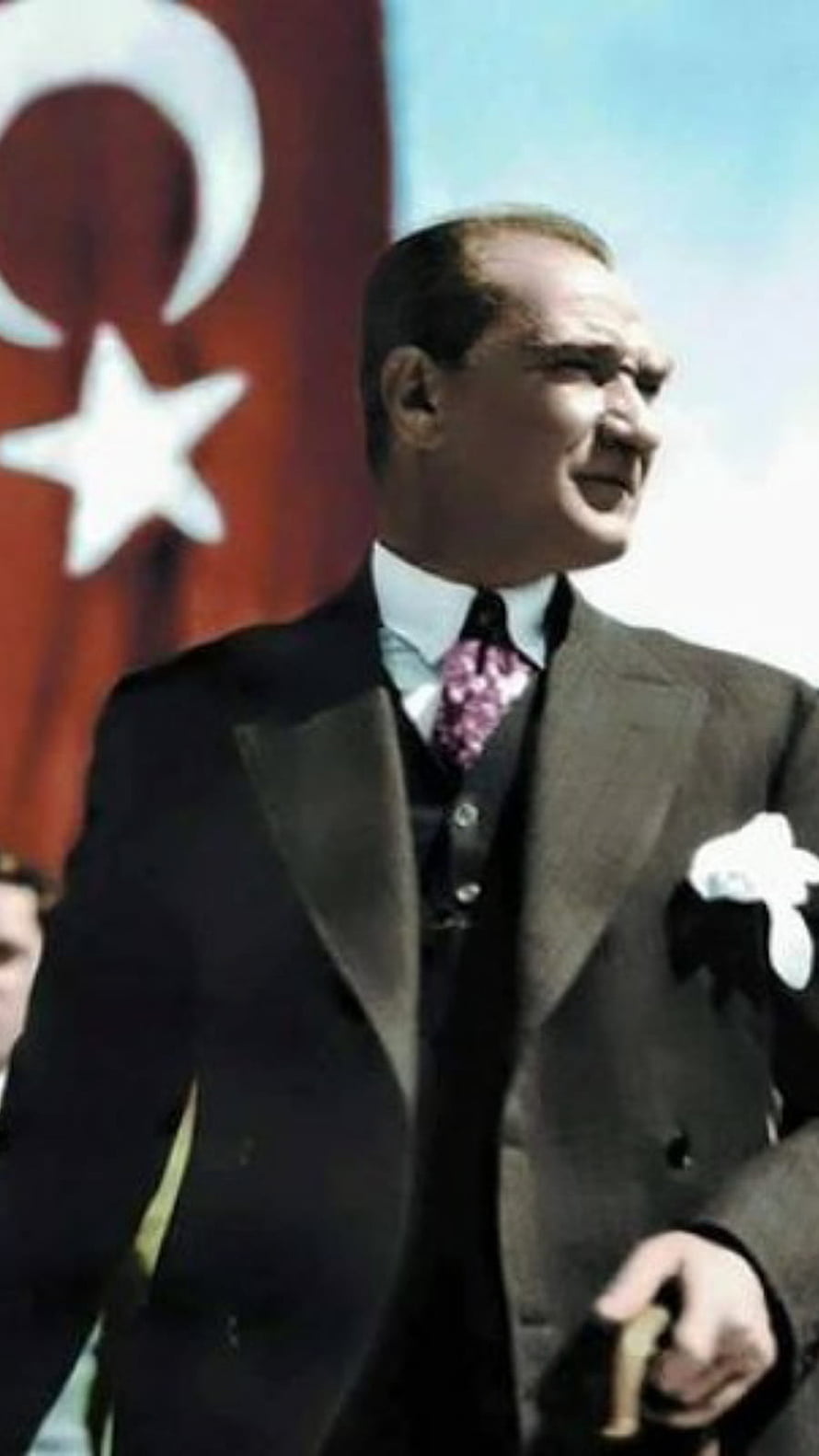Mustafa Kemal Atatürk in a formal suit standing before the Turkish national flag HD phone wallpaper