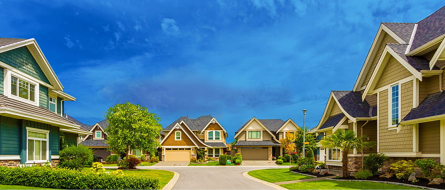 Suburban Neighborhood Street With Modern Homes And Lush Green Lawns Under A Blue Sky HD wallpaper