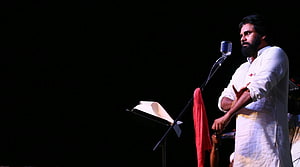 Janasenani P. S. P. K. performing on stage in white kurta with vintage microphone HD wallpaper