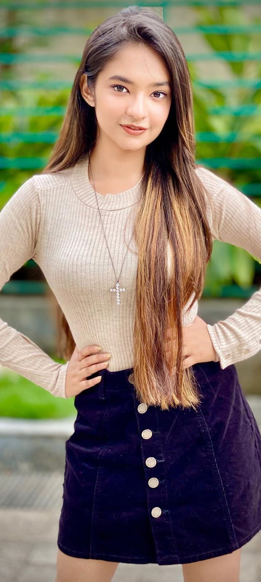 Anushka Sen in a beige ribbed top and dark buttoned skirt with a cross necklace HD phone wallpaper