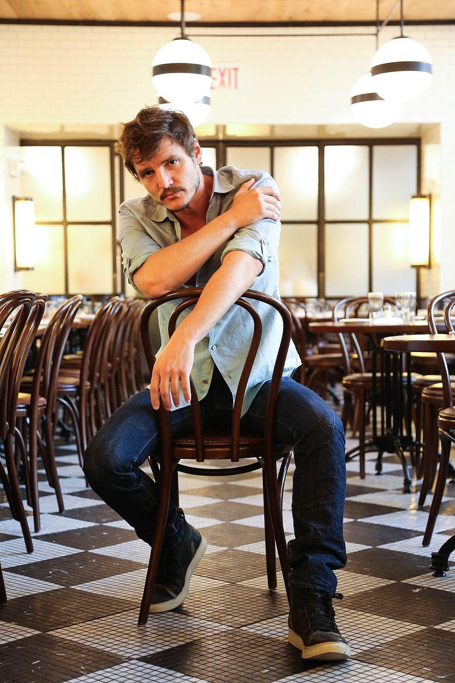 Pedro Pascal seated in a vintage cafe with checkered floor and wooden chairs HD phone wallpaper