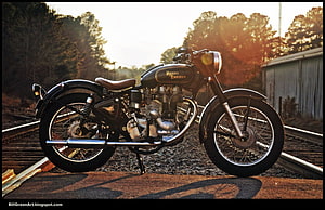 Classic Royal Enfield Bullet Motorcycle Parked on Rustic Railroad Tracks at Golden Hour HD wallpaper