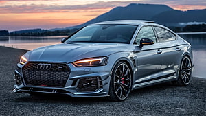 Silver Audi RS5 Sportback parked on gravel at sunset with mountain backdrop HD wallpaper