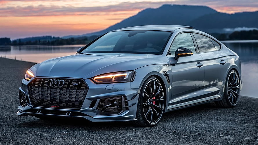 Silver Audi RS5 Sportback parked on gravel at sunset with mountain backdrop HD wallpaper