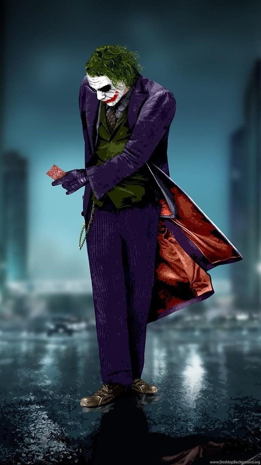 The Joker in a purple suit holding a playing card in a rainy cityscape HD phone wallpaper