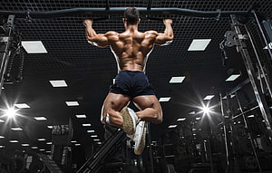 Muscular Male Athlete Performing Pull-Up on Gym Horizontal Bar HD wallpaper