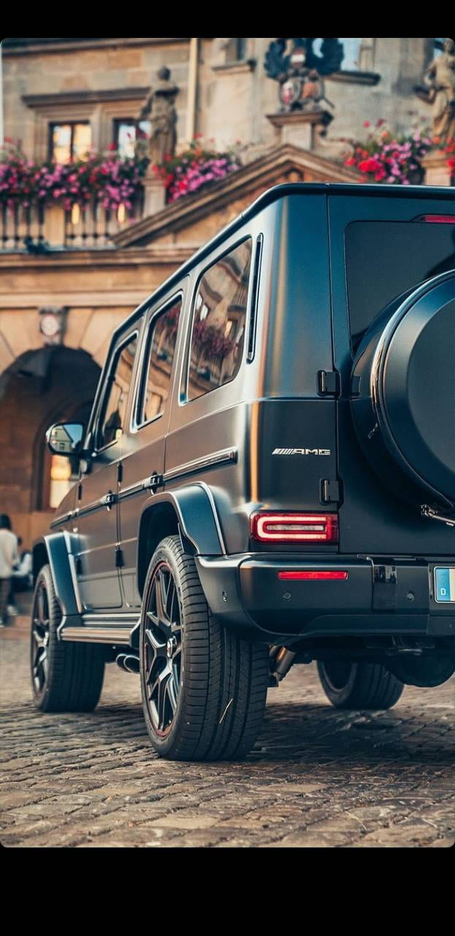 Rear Three-Quarter View of a Black Mercedes-AMG G63 SUV Parked on Cobblestones in a European City HD phone wallpaper
