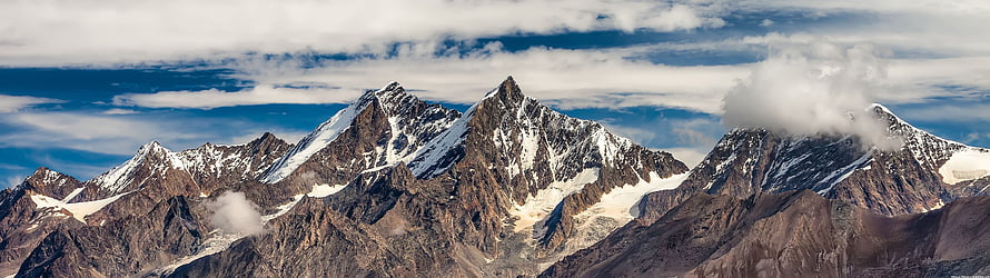Majestic Snow-Capped Mountain Peaks Rising Above Clouds in a Dramatic Alpine Landscape HD wallpaper