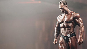 Muscular Male Bodybuilder Posing On Stage With Tanned Skin And Black Trunks HD wallpaper