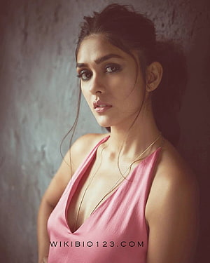 Mrunal Thakur in a pink halter top with a soft studio portrait against a textured wall HD phone wallpaper