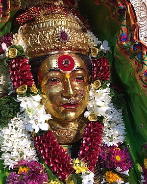 Golden Goddess Statue Adorned with Floral Garlands and Traditional Jewelry HD phone wallpaper