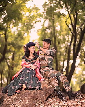 Indian Army Soldier and Wife in Traditional Attire Sitting on a Rock in a Forest HD phone wallpaper