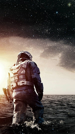 Interstellar astronaut standing in water beneath a star-filled cosmic sky HD phone wallpaper