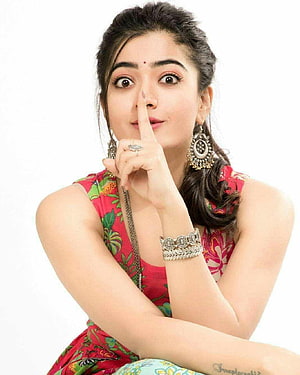 Rashmika Mandanna in a red floral dress with traditional Indian jewelry and a playful shush gesture HD phone wallpaper