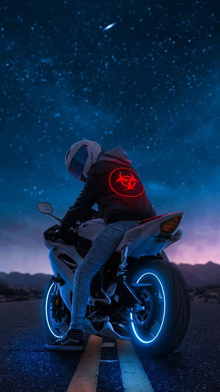 Biker with glowing red biohazard hoodie on neon motorcycle under starry night sky HD phone wallpaper
