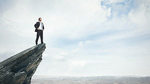 Businessman standing on a rocky cliff edge overlooking a vast landscape under a cloudy sky, Motivational and Inspirational Backgrounds Music For Videos, motivation background HD wallpaper