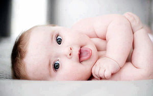 Cute Baby Lying Down With Tongue Out And Big Blue Eyes HD wallpaper