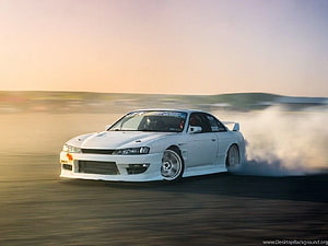 White Nissan Silvia S14 drifting on an open track at sunset with tire smoke HD wallpaper