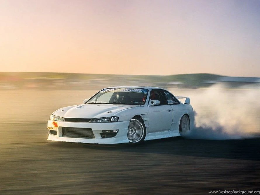 White Nissan Silvia S14 drifting on an open track at sunset with tire smoke HD wallpaper