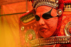 Traditional Theyyam Ritual Performance with Elaborate Face Paint and Ornate Costume HD wallpaper
