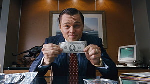 Leonardo DiCaprio as Jordan Belfort holding a dollar bill in The Wolf of Wall Street HD wallpaper