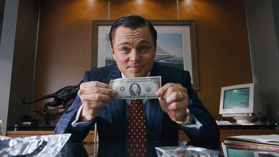 Leonardo DiCaprio as Jordan Belfort holding a dollar bill in The Wolf of Wall Street HD wallpaper