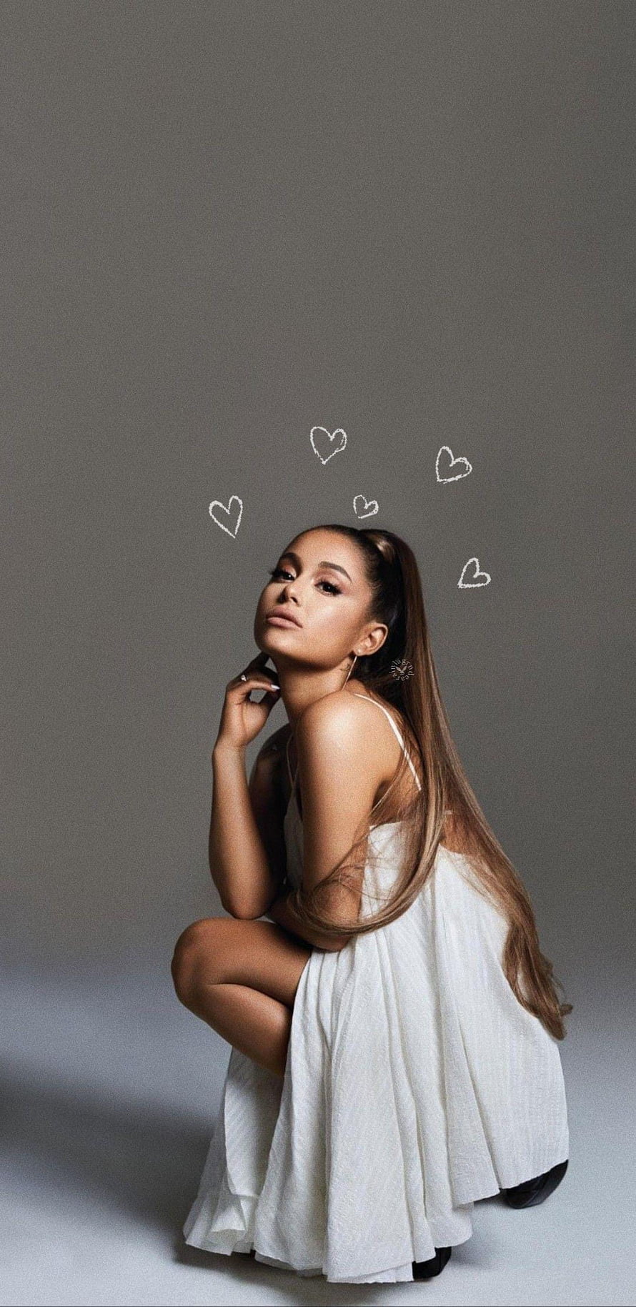 Ariana Grande in a flowing white dress with hand-drawn hearts against a neutral gray studio backdrop HD phone wallpaper