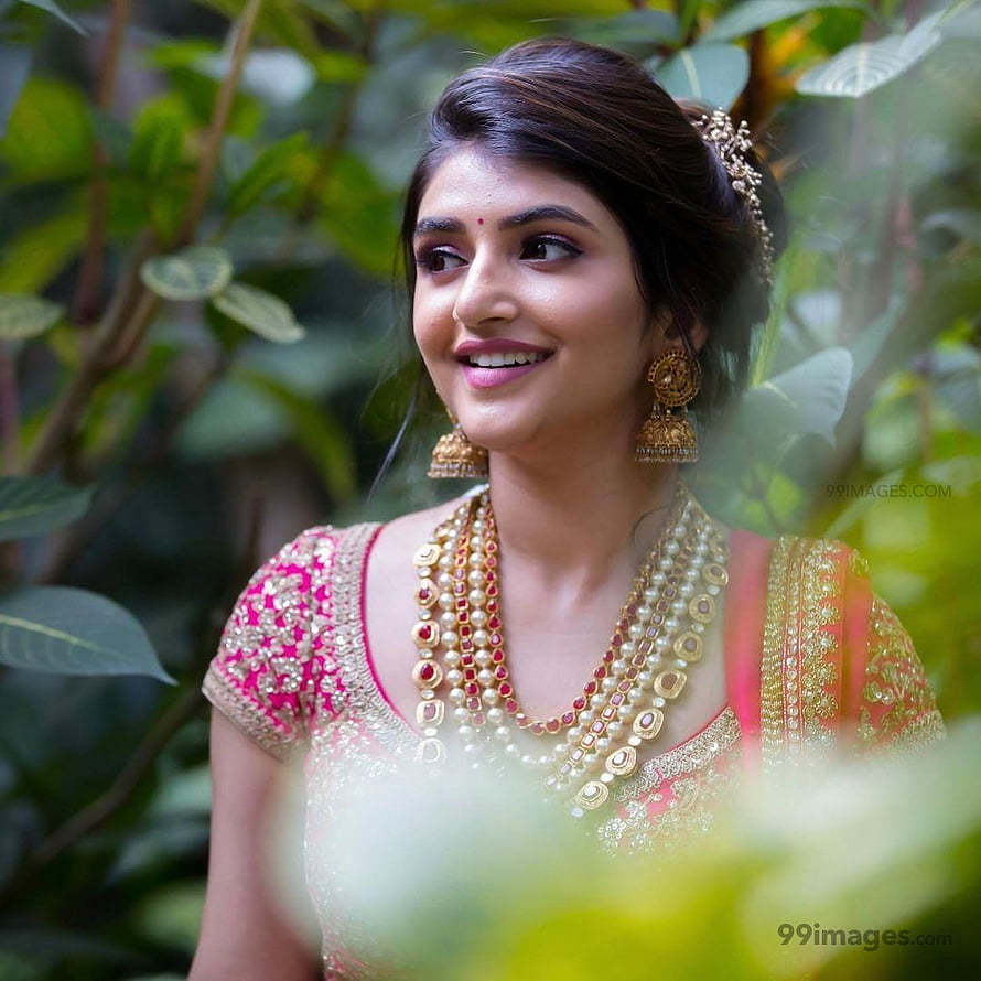 Sree Leela in Traditional Indian Attire with Gold Jewelry and Floral Background HD phone wallpaper