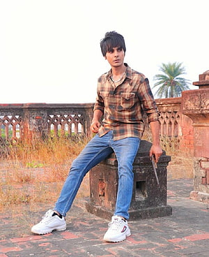 Young man in plaid shirt and jeans sitting on stone block holding a pistol, Jay Randhawa Wiki, Biography, Age & More in 2020, sukha HD phone wallpaper