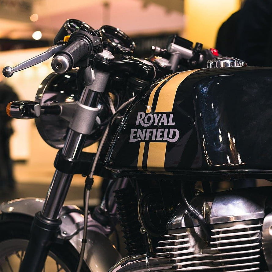 Close-up of a black Royal Enfield motorcycle with gold stripes on the fuel tank and chrome engine details HD phone wallpaper
