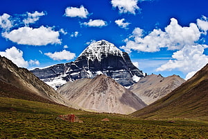 Mount Kailash Sacred Peak Rising Above High-Altitude Grasslands Under a Vivid Blue Sky HD wallpaper
