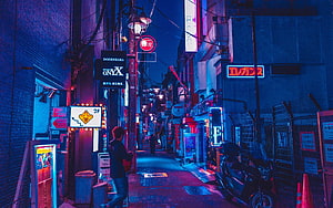Neon-lit Tokyo alleyway at night with vibrant blue and pink lights, featuring a lone figure walking past glowing signs and a parked scooter in a cyberpunk-inspired urban scene HD wallpaper
