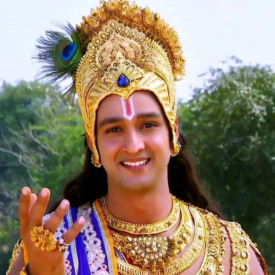 Krishna with peacock feather crown and golden jewelry smiling portrait HD phone wallpaper