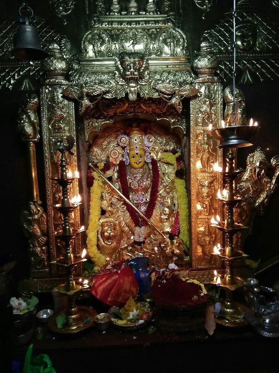 Golden Goddess Durga Idol in Temple Shrine with Oil Lamps and Floral Offerings HD phone wallpaper