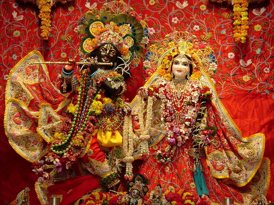 Radha Krishna Deities Adorned in Flowers and Jewels on Red Embroidered Backdrop HD wallpaper
