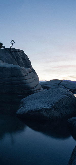 Serene Granite Boulders and Solitary Pine Tree at Twilight in a Mountain Lake HD phone wallpaper